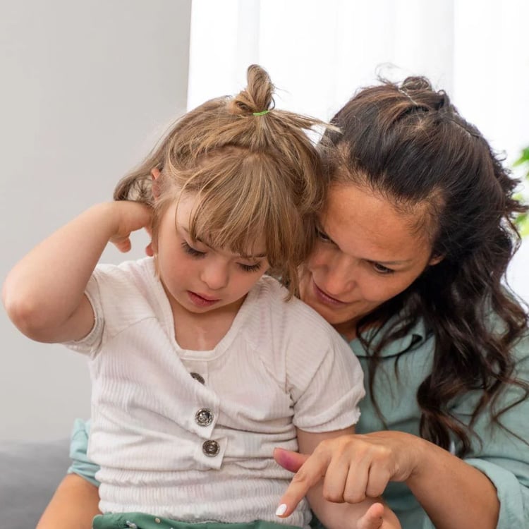 Jente og mamma som sitter tett sammen og peker – nærhet, støtte og læring i hverdagen.