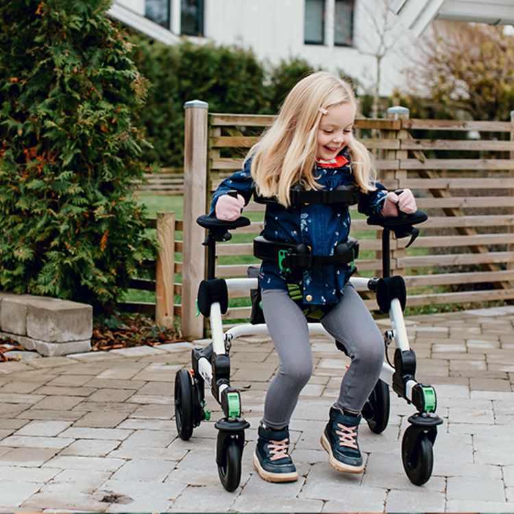 Jente som går med et ganghjelpemiddel på en gårdsplass – trygghet og selvstendighet i bevegelse.