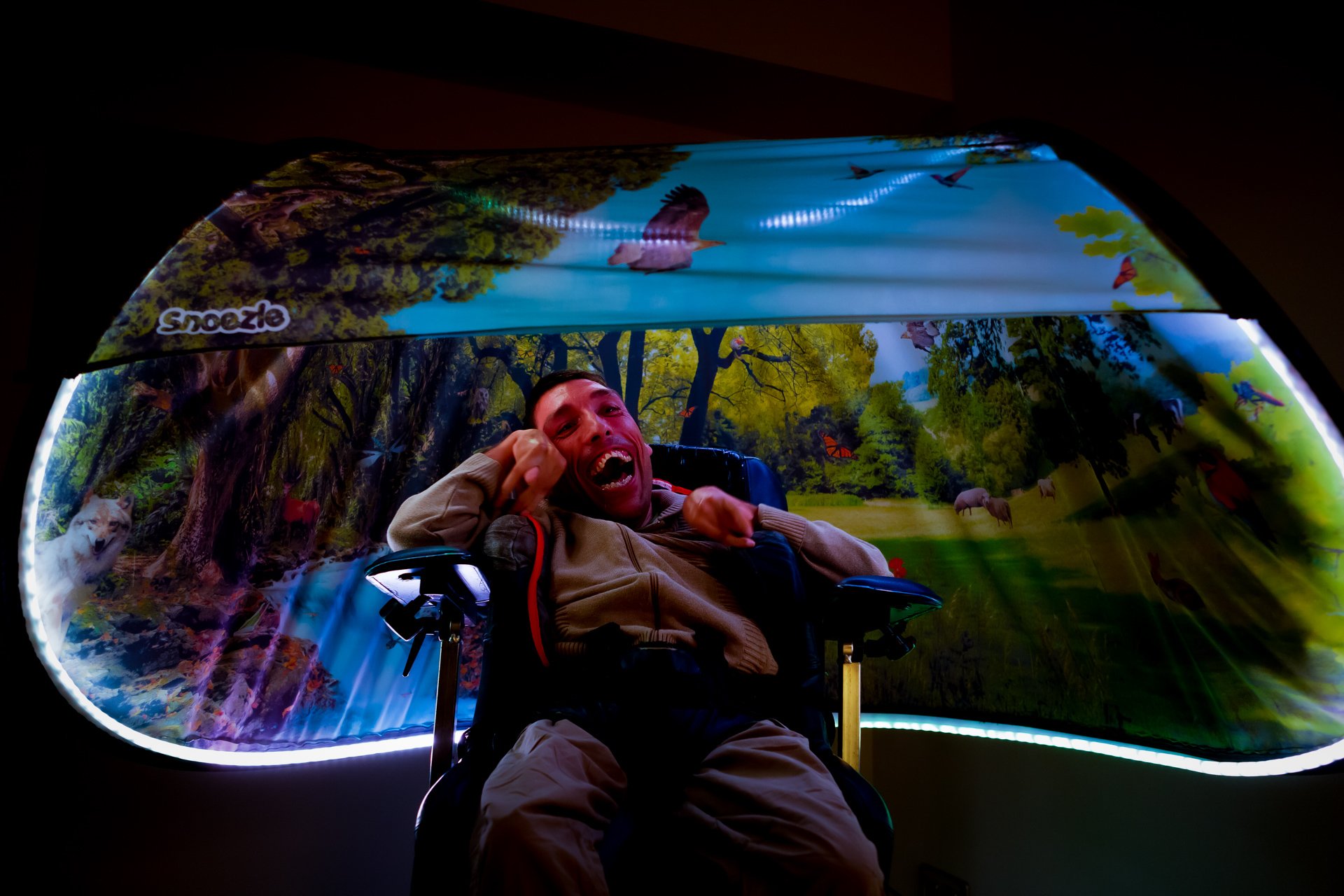 Bruker i rullestol under Snoezle-telt med skogmotiv og grønt lys.