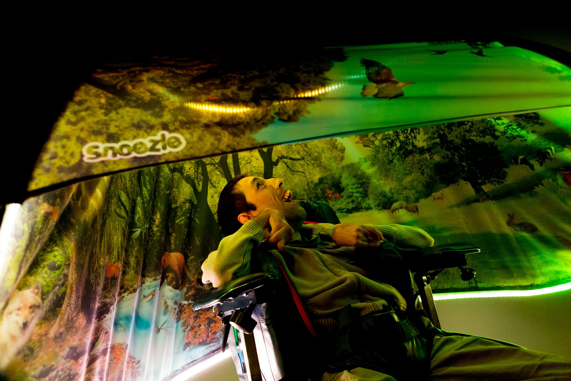 Person i rullestol hviler under Snoezle-telt med dempet grønn belysning.