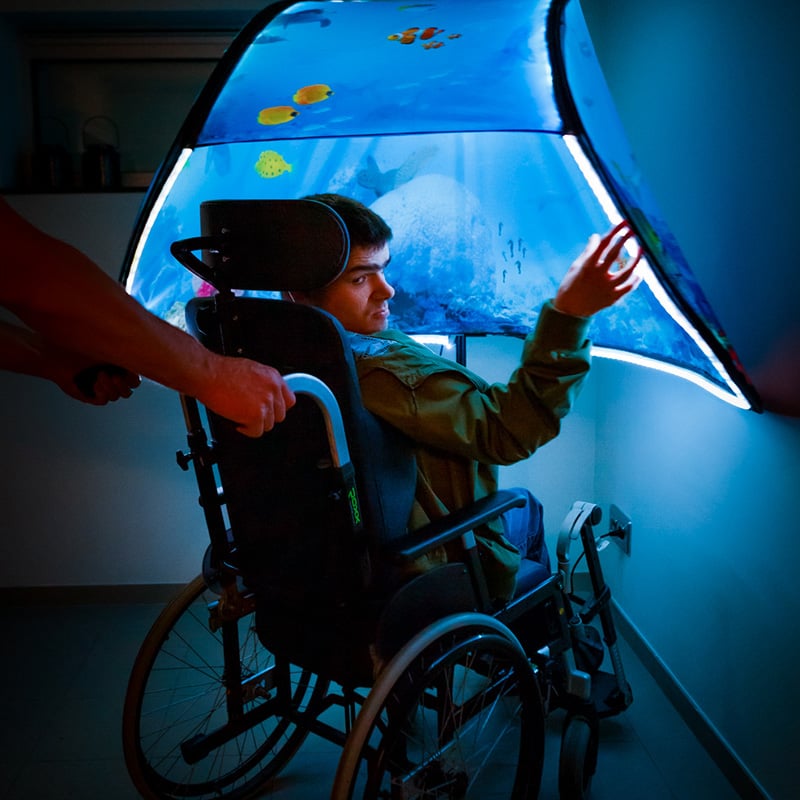Person i rullestol bruker Snoezle sansetelt med myk blå belysning.