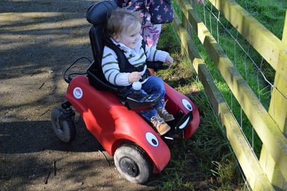 En liten gutt hygger seg på tur i sin elektriske WizzyBug-rullestol.