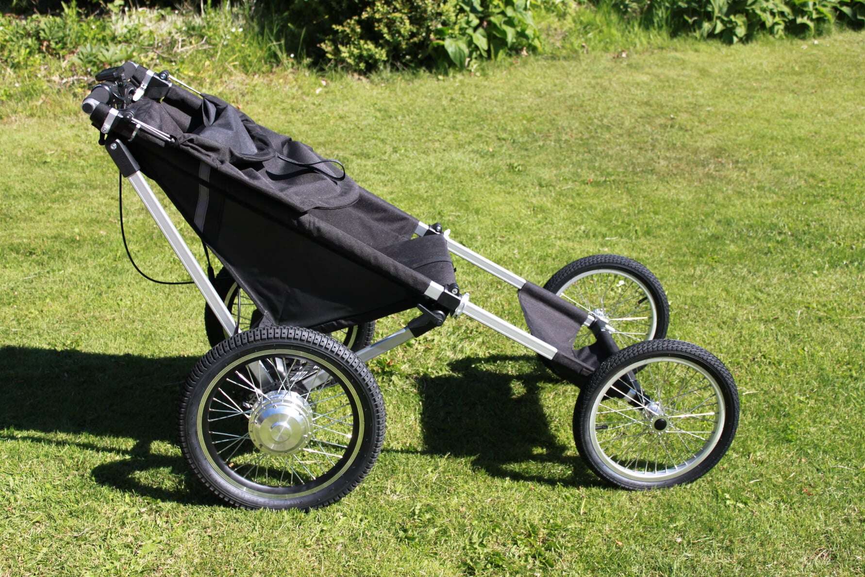 Terrengvogn KFN 4Wheeler Explorer for funksjonshemmede barn og voksne, sett fra siden, stående på gress.