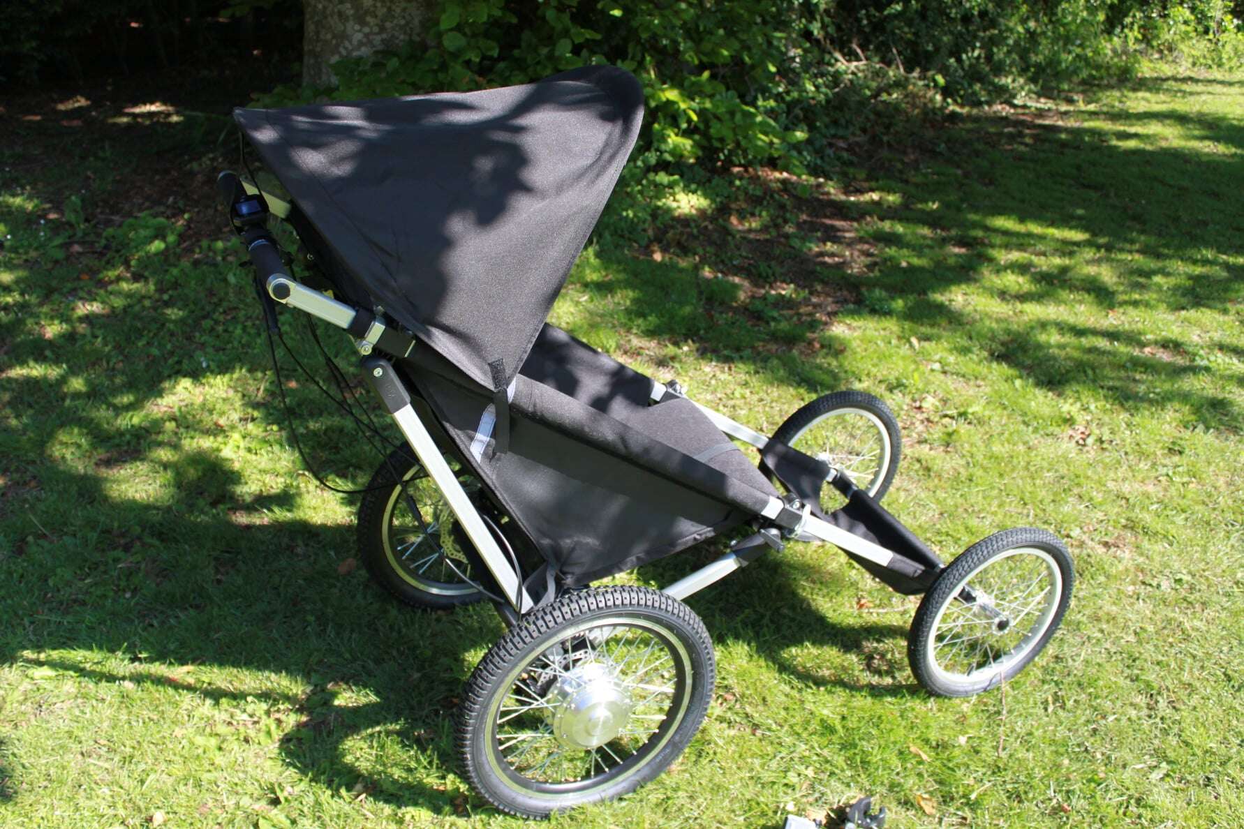 Terrengvogn KFN 4Wheeler Explorer for funksjonshemmede barn og voksne med kalesje, sett fra siden, stående på gress.